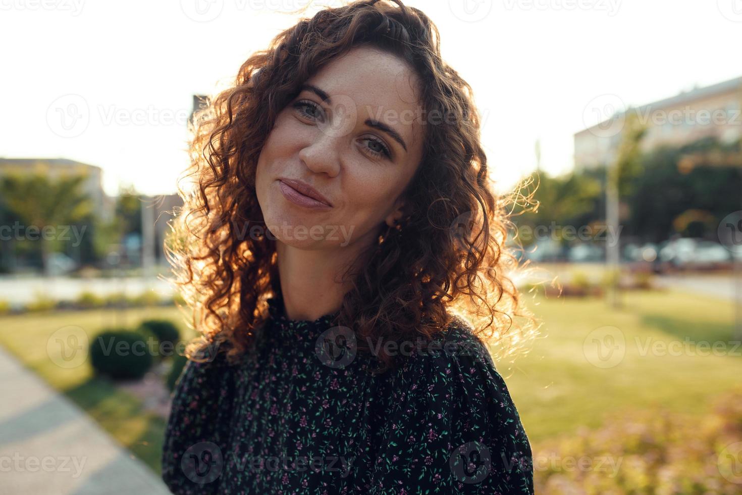 Portraits of a charming red-haired girl with freckles and a pretty face. The girl poses for the camera in the city center. She has a great mood and a sweet smile photo