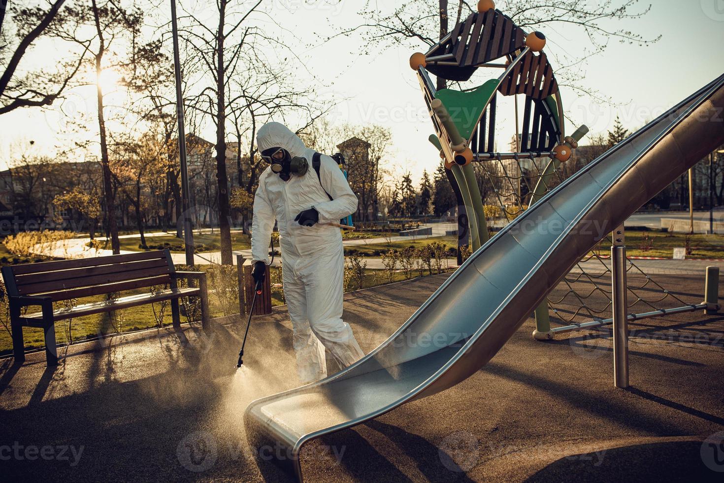 Cleaning and Disinfection on the playground in the sity complex amid the coronavirus epidemic Teams for disinfection efforts Infection prevention and control of epidemic Protective suit and mask photo