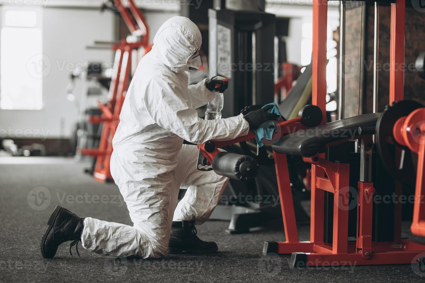 Cleaning and Disinfection in crowded places amid the coronavirus epidemic Gym cleaning and disinfection Infection prevention and control of epidemic. Protective suit and mask and spray bag photo