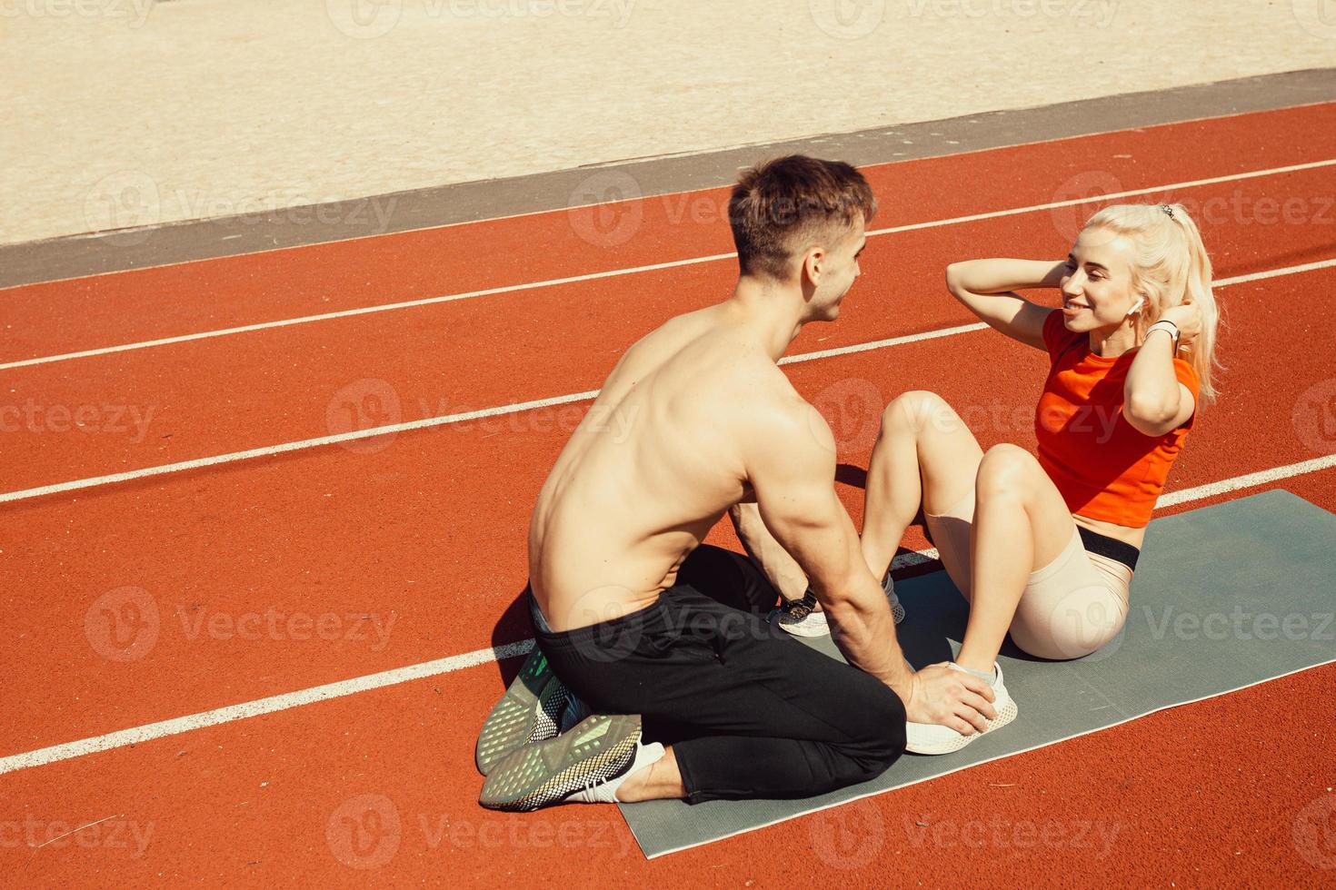 Una pareja joven bombea los músculos abdominales en una alfombra de yoga foto