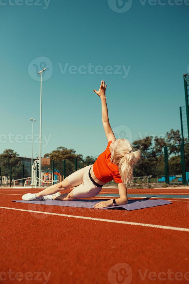 pareja joven haciendo deporte en el estadio acostado en colchonetas de yoga foto