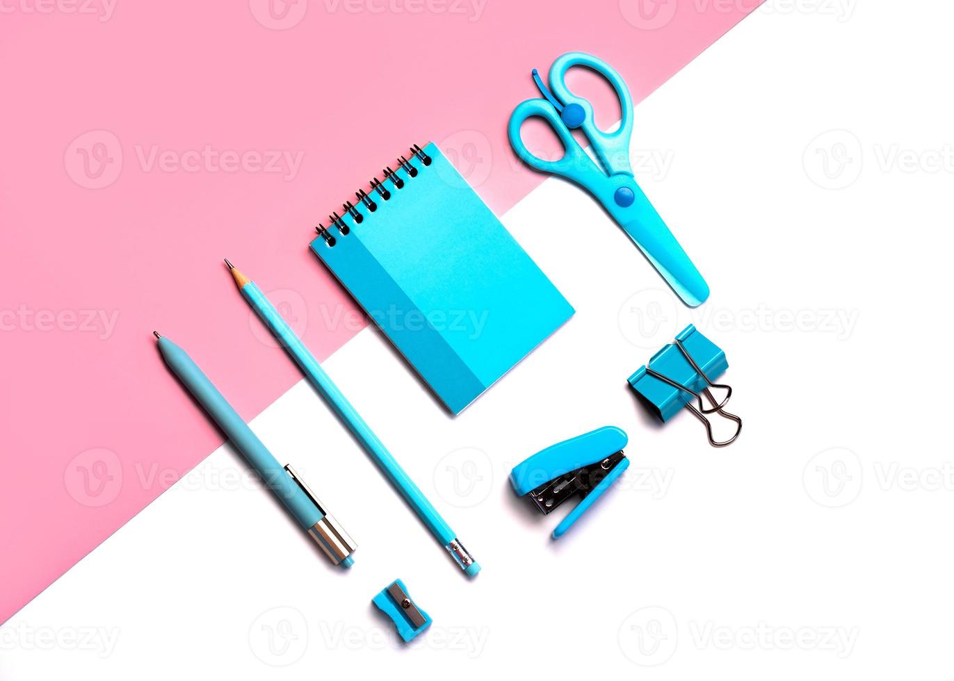 vista superior plana de tijeras, lápiz, clips de papel, grapadora, sacapuntas, bolígrafo con bloc de notas azul.concepto de papelería escolar foto