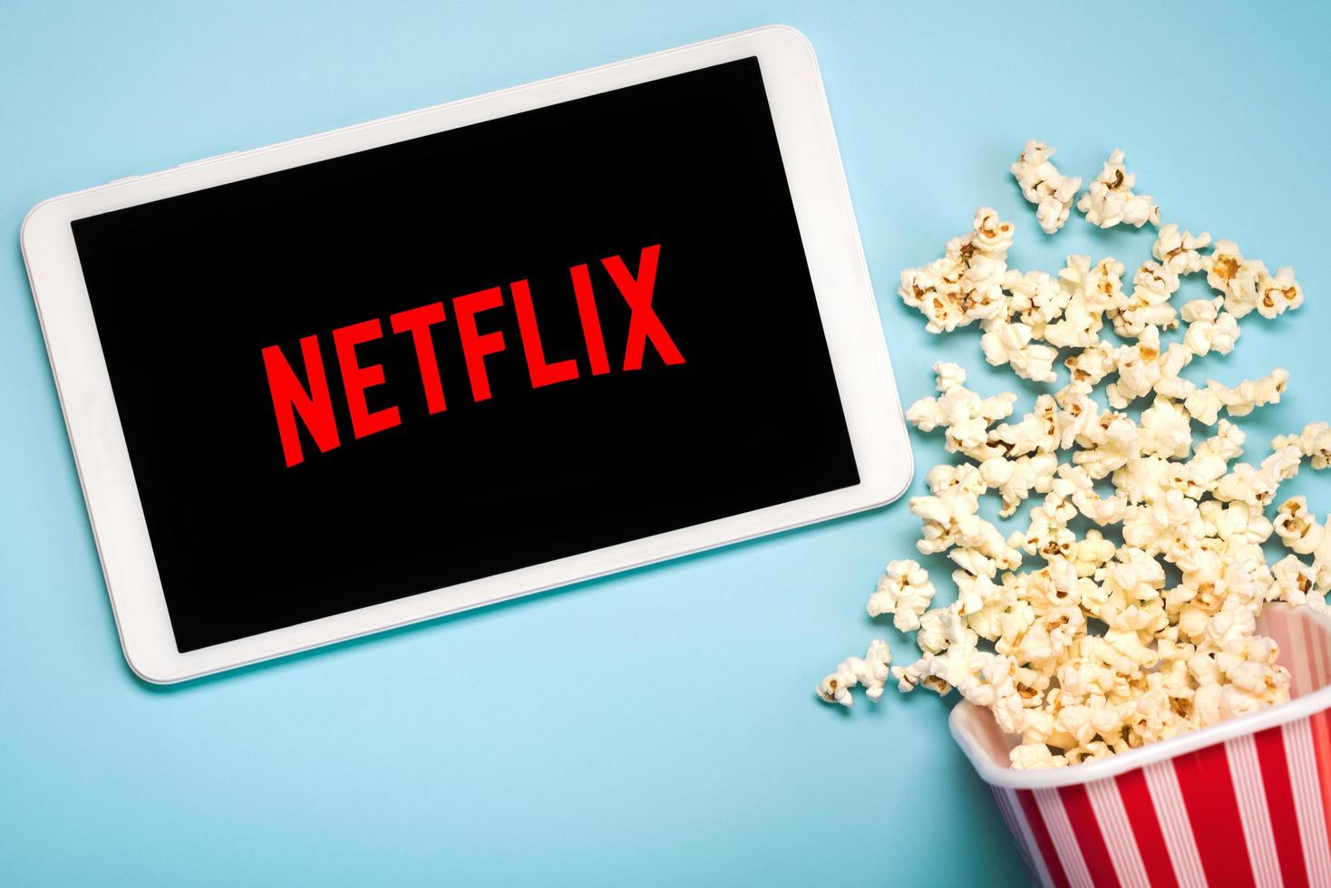 Netflix logo on the screen of a white digital tablet with popcorn photo