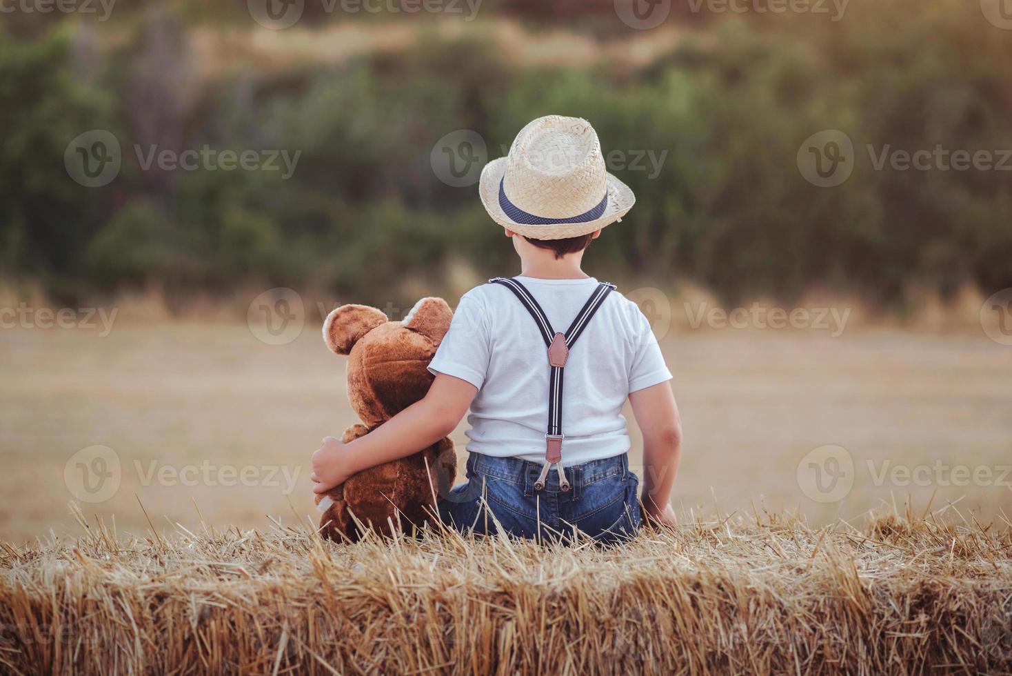 Boy hugging teddy bear in the wheat field photo