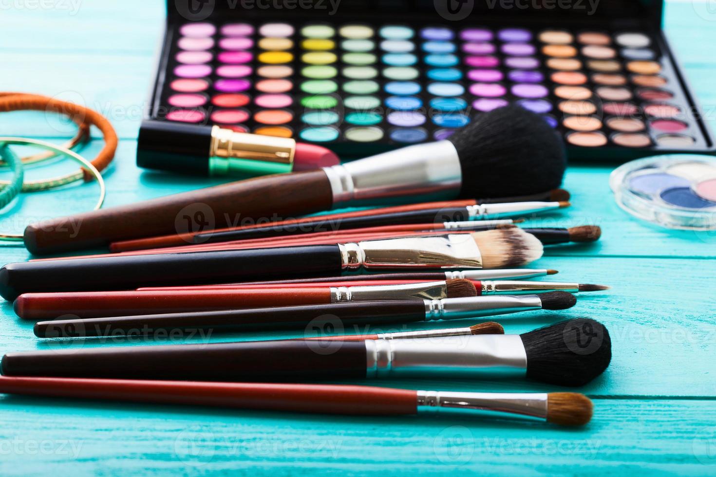 Make-up tools. Make up products. Lipstick, eye shadow, brushes. Cosmetics on blue wooden background. Selective focus photo