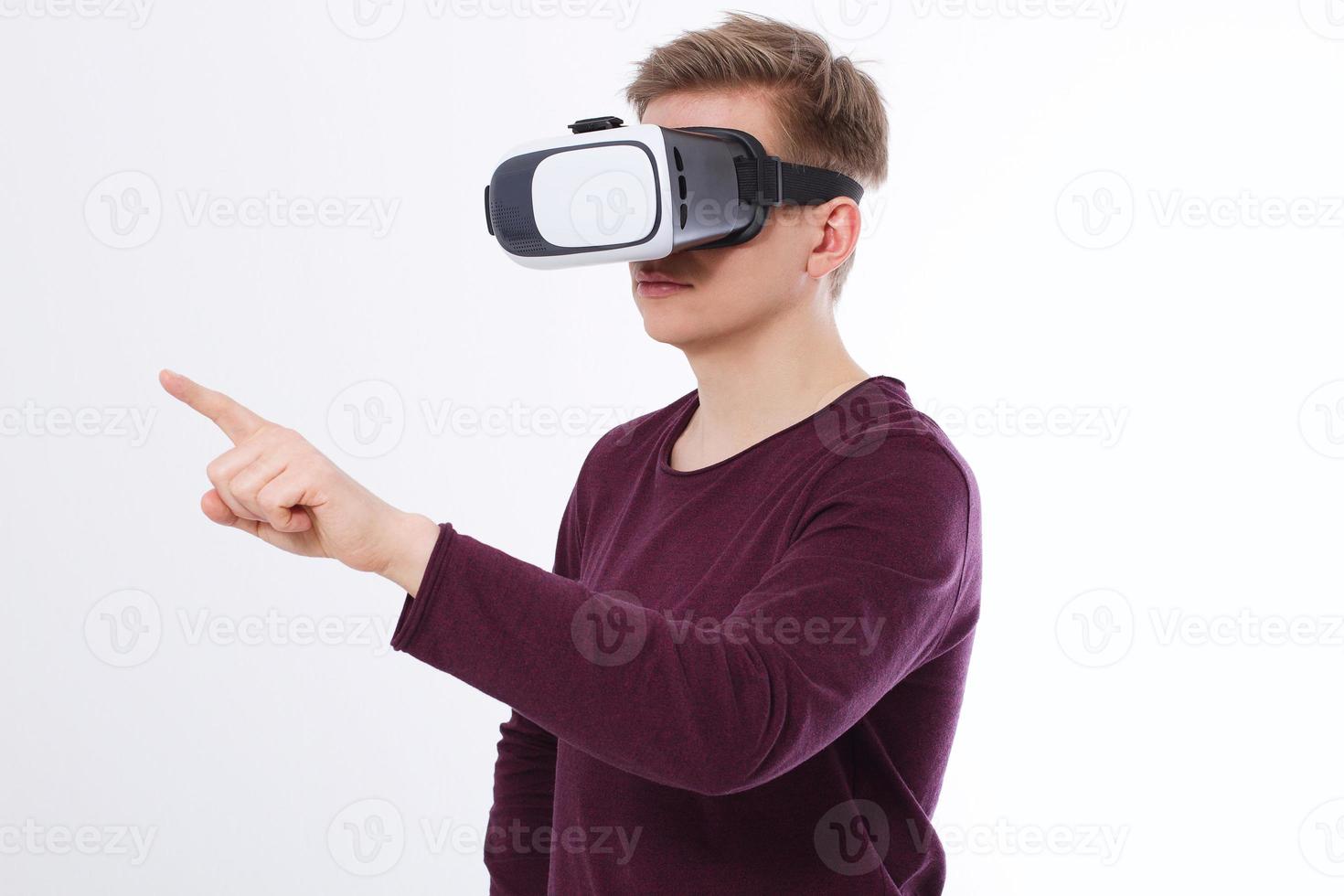Young Man wearing virtual reality goggles and toch space by finger isolated on white background. VR concept and copy space. Selective focus. Blank template Shirt. photo