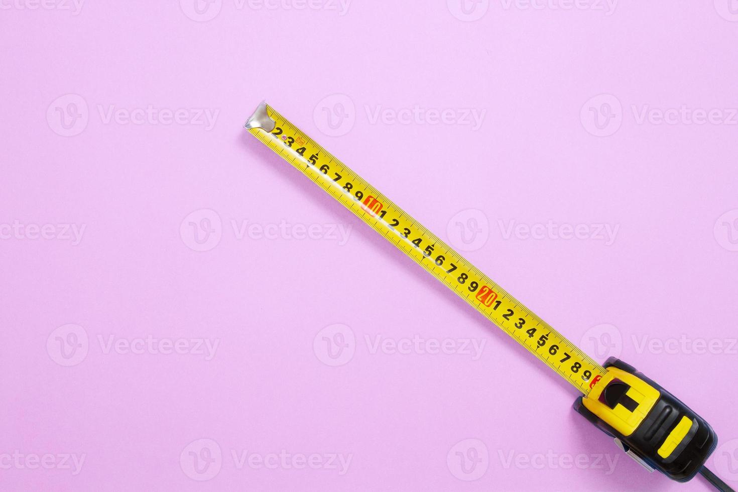 Yellow Tape measure on pastel pink background. Top view and mock up. Building accessories and tool. Copy space photo