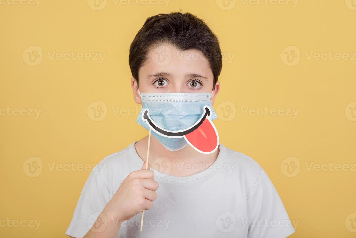 niño con máscara médica y sonrisa falsa en el palo foto