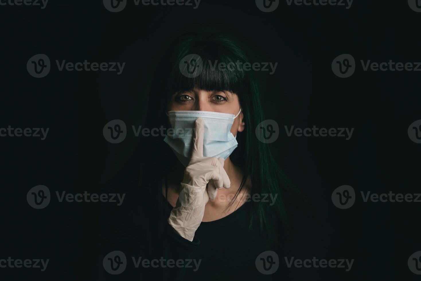 mujer joven con mascarilla médica pidiendo silencio foto