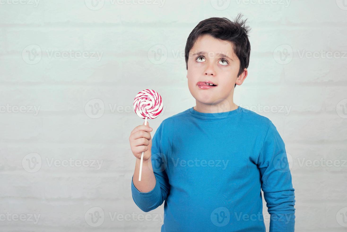 Funny thinking kid with lollipop photo
