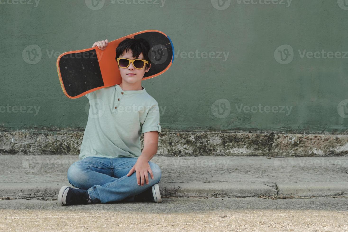 niño feliz con monopatín y gafas de sol foto