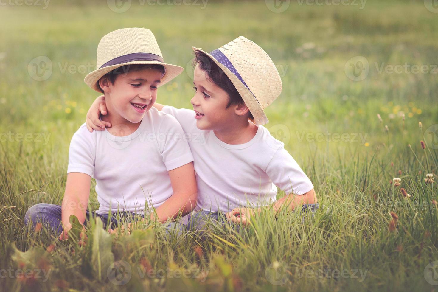 hermanos sonrientes sentados en la hierba foto