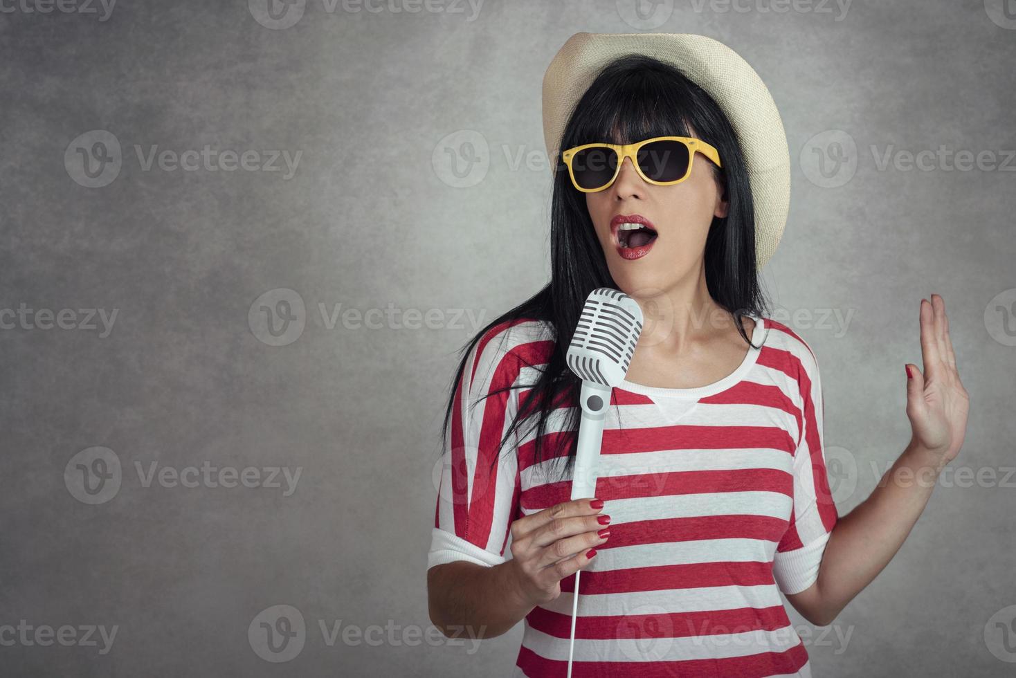 mujer joven sosteniendo un micrófono cantando foto