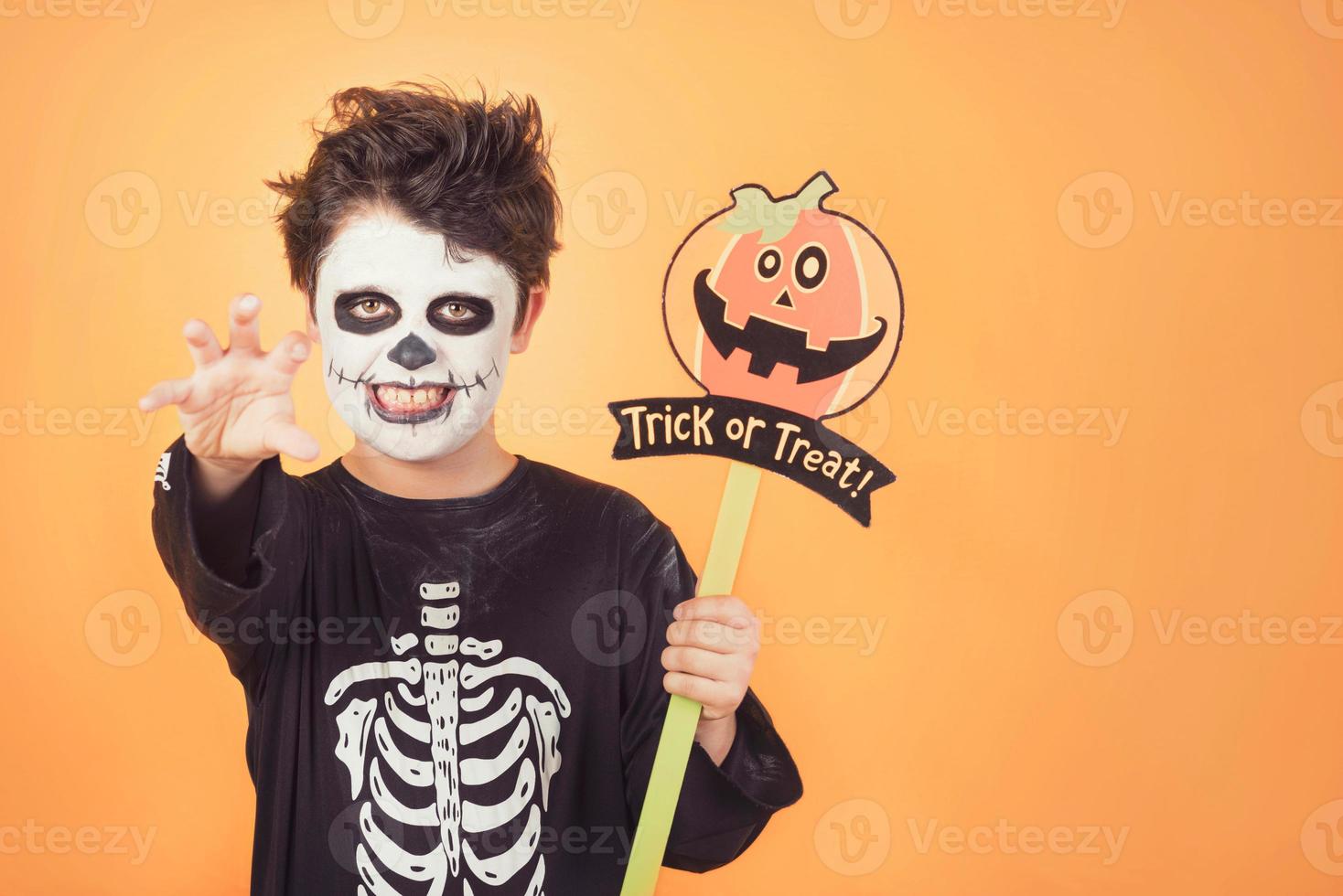 truco o trato. niño divertido en un disfraz de esqueleto con calabaza de halloween foto