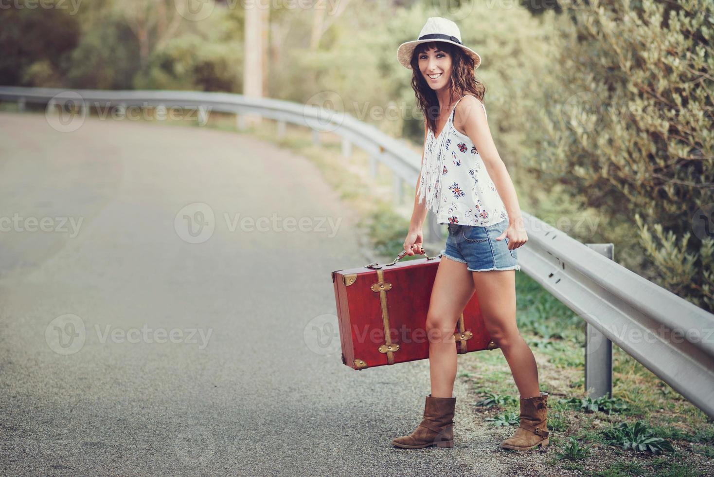 Young girl with a suitcase on the road photo