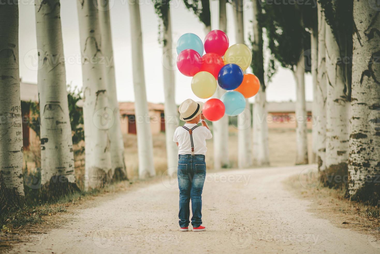 Back view of thoughtful child with balloons in the in the path photo