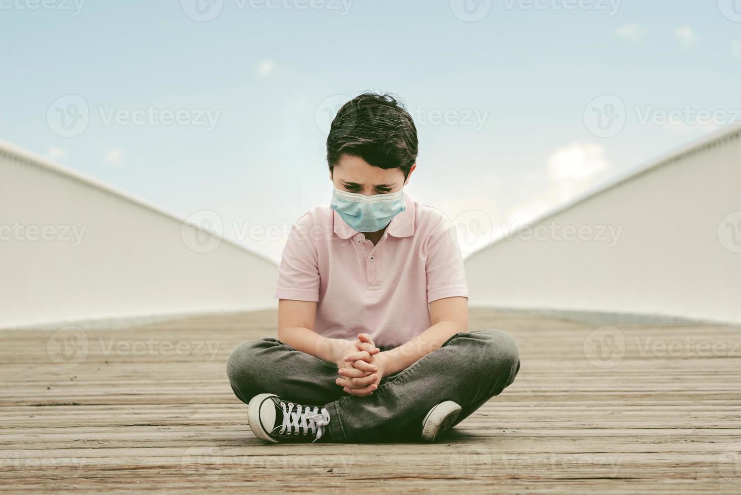 sad and thoughtful kid wearing medical mask photo