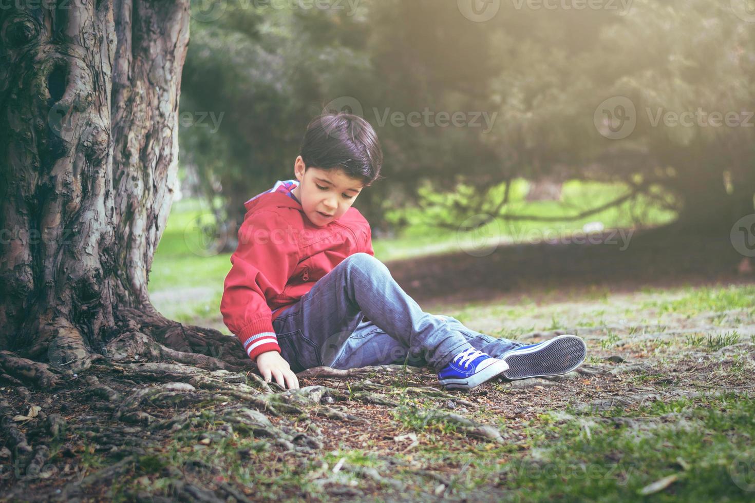 thoughtful child sitting on field photo