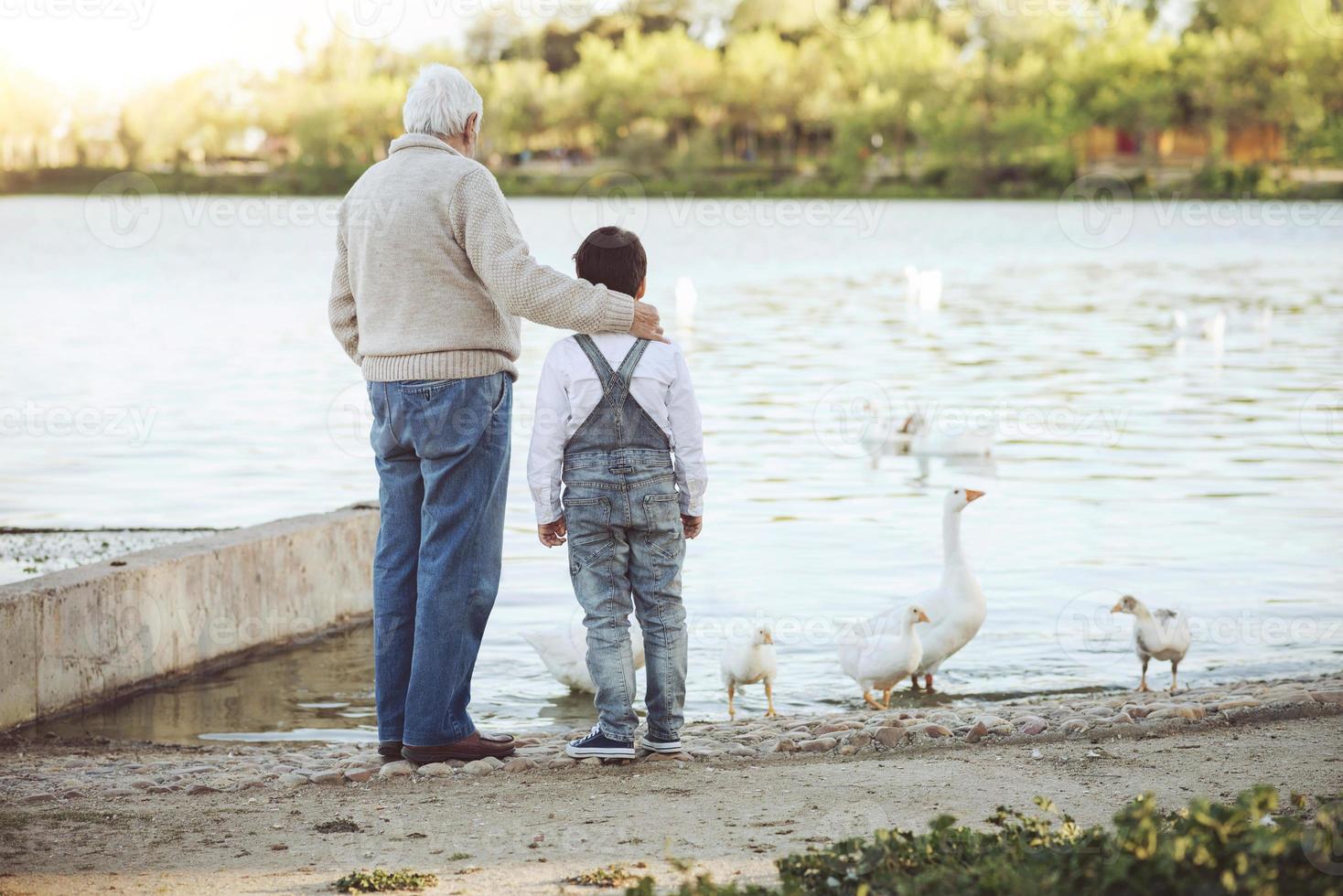 Grandfather With His grandson on the lake. Back view photo