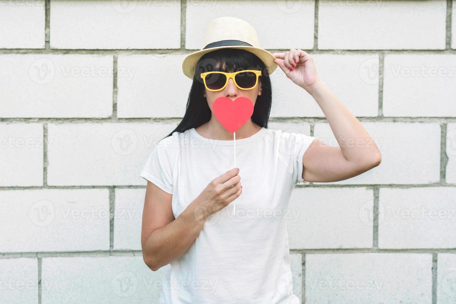 Hipster girl with red heart on brick background photo