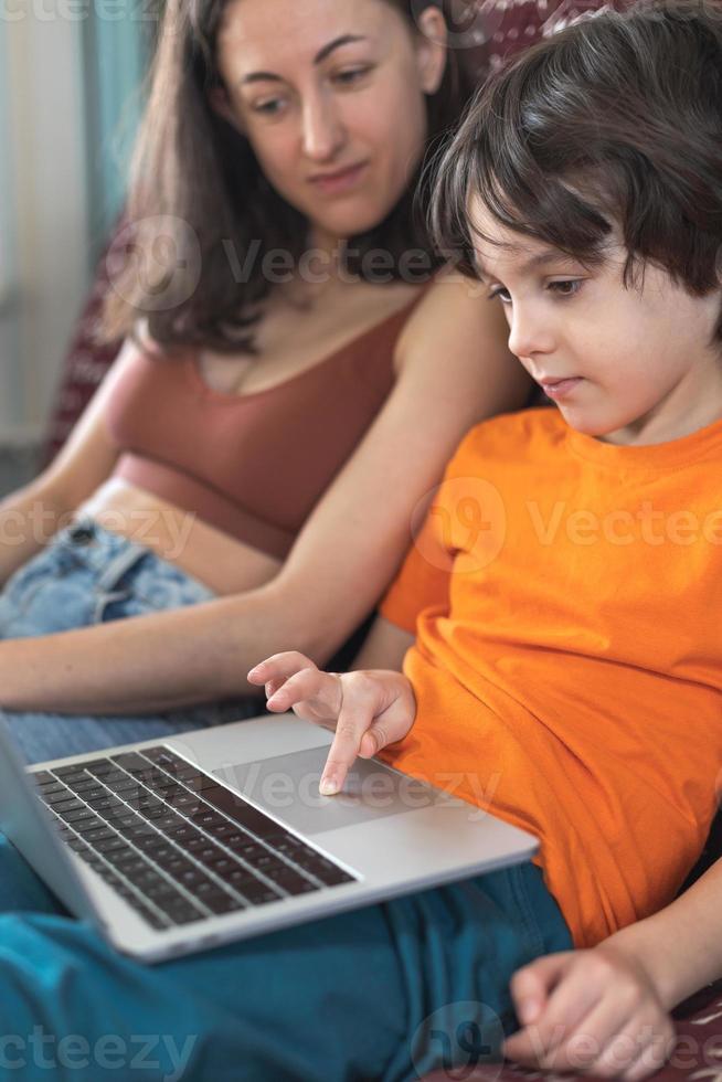 a woman with a child is sitting at a laptop photo