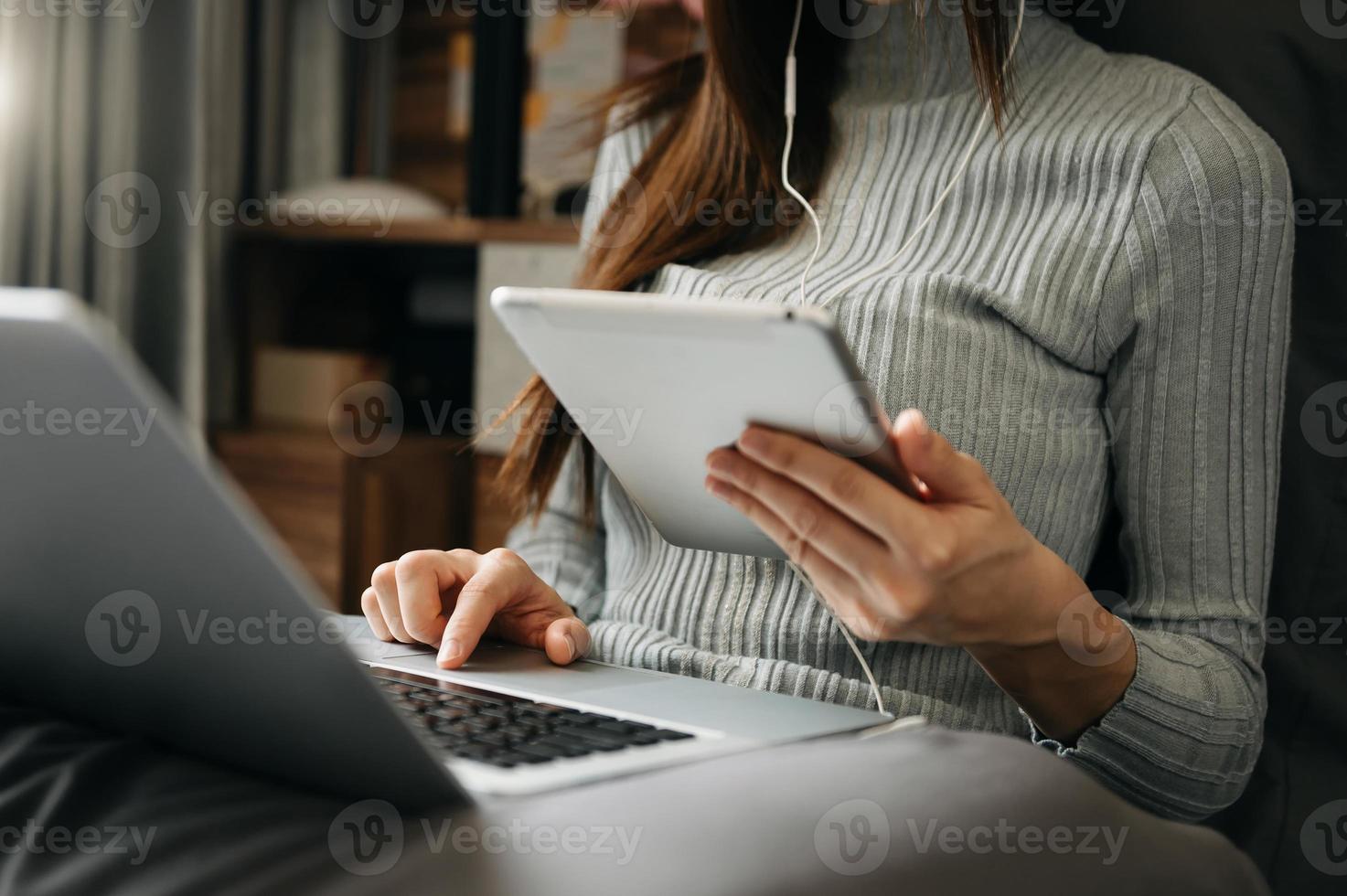 las manos de la mujer están escribiendo en una computadora portátil y sosteniendo un teléfono inteligente en la oficina foto