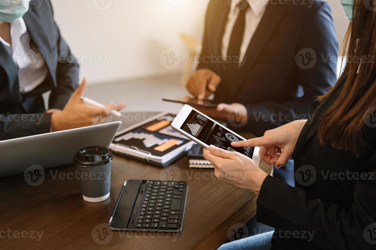 documentos comerciales en la mesa de la oficina con teléfono inteligente y calculadora tableta digital y negocios gráficos con diagrama de red social y dos colegas discutiendo datos trabajando en la oficina foto