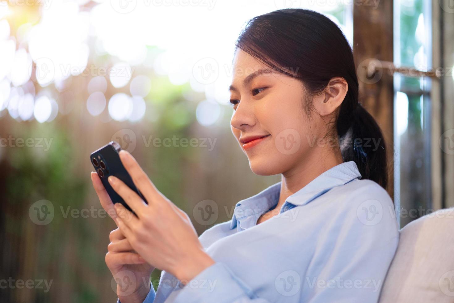 Beautiful young Asian woman using her phone to text her friend photo