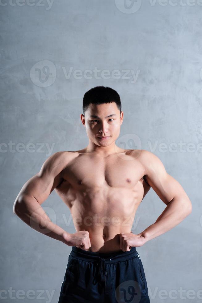 Muscular Asian man posing on gray background photo