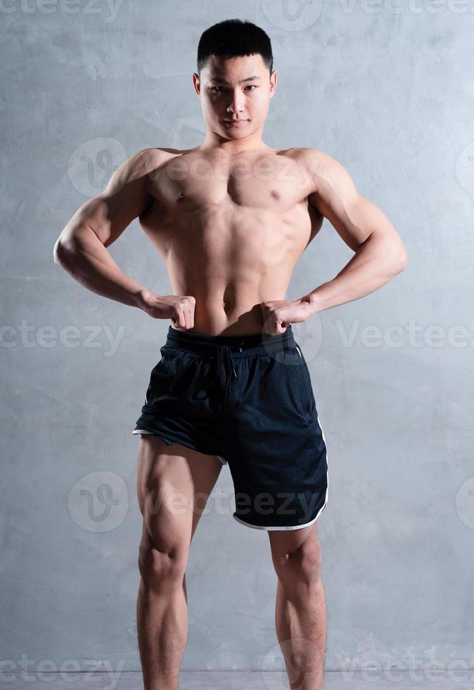 Muscular Asian man posing on gray background photo