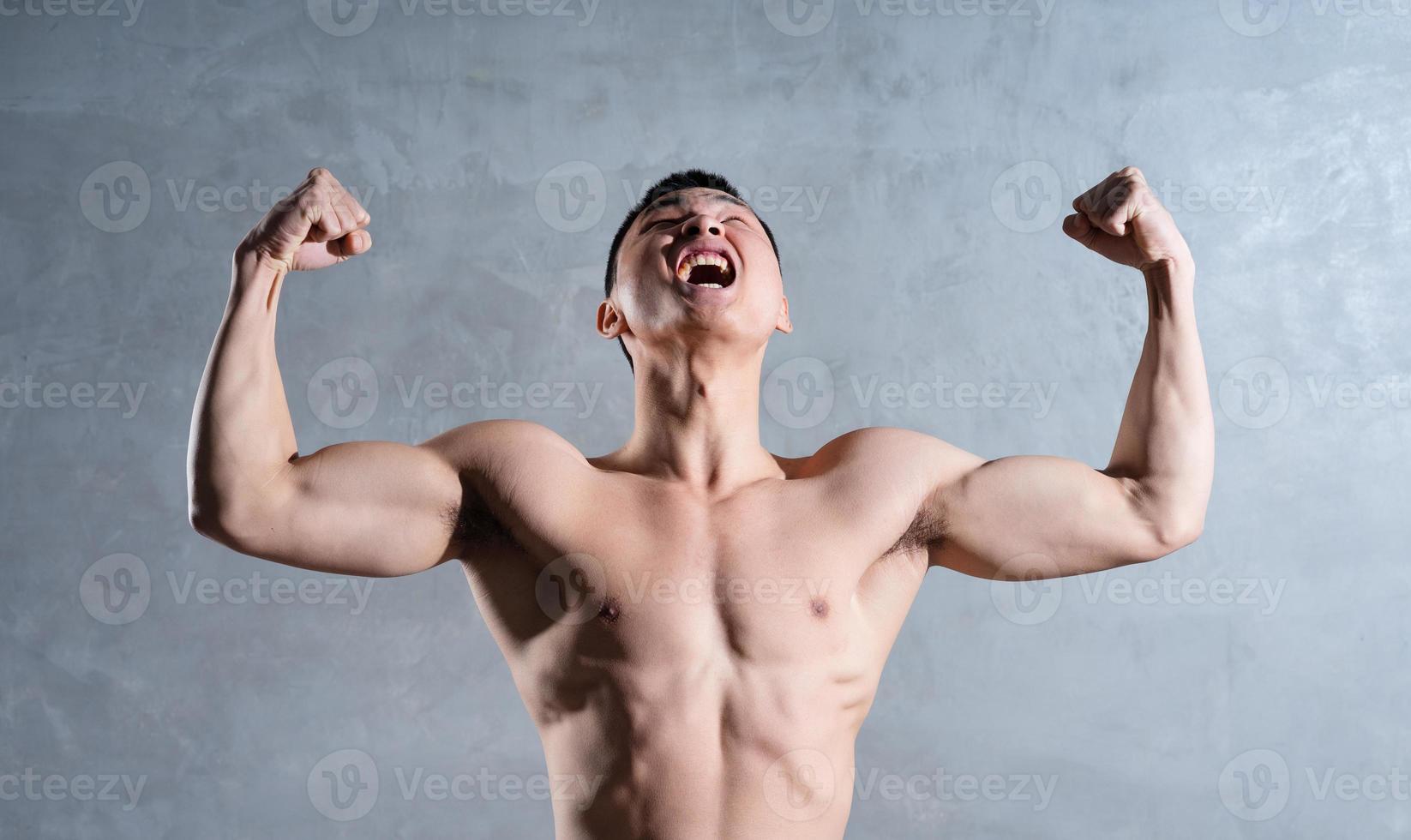 hombre asiático musculoso posando sobre fondo gris foto