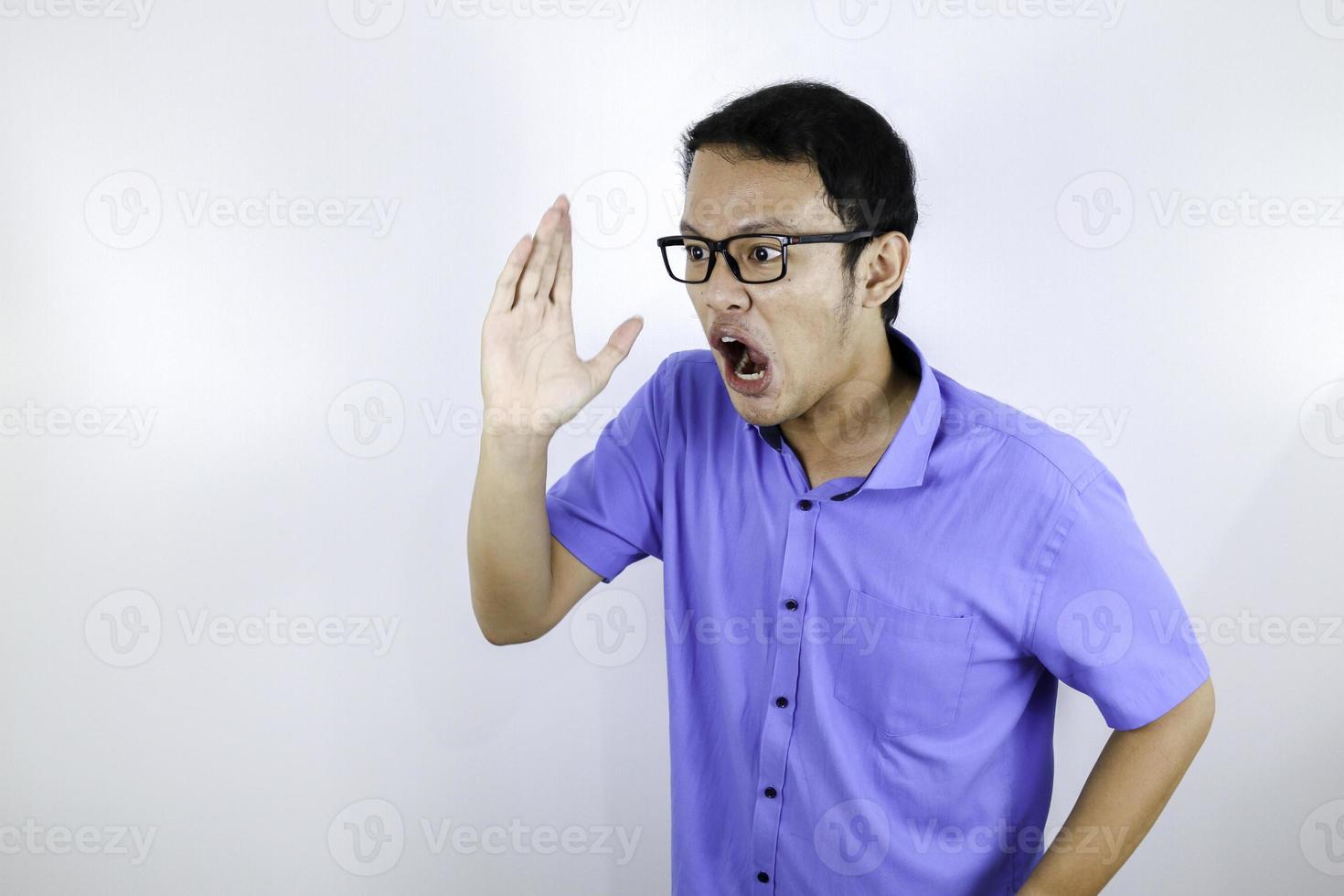 Close up portrait of a young asian man shouting loud and angry facce with arm at his face isolated over white photo