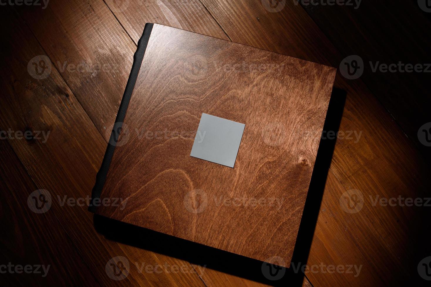 Photo book in a wooden cover on a wooden table. Hard light