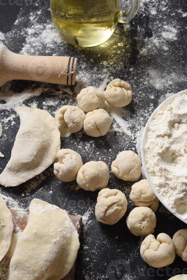 Pieces of dough in the form of a circle on a black background. Modeling of dumplings. Traditional Ukrainian cuisine. photo