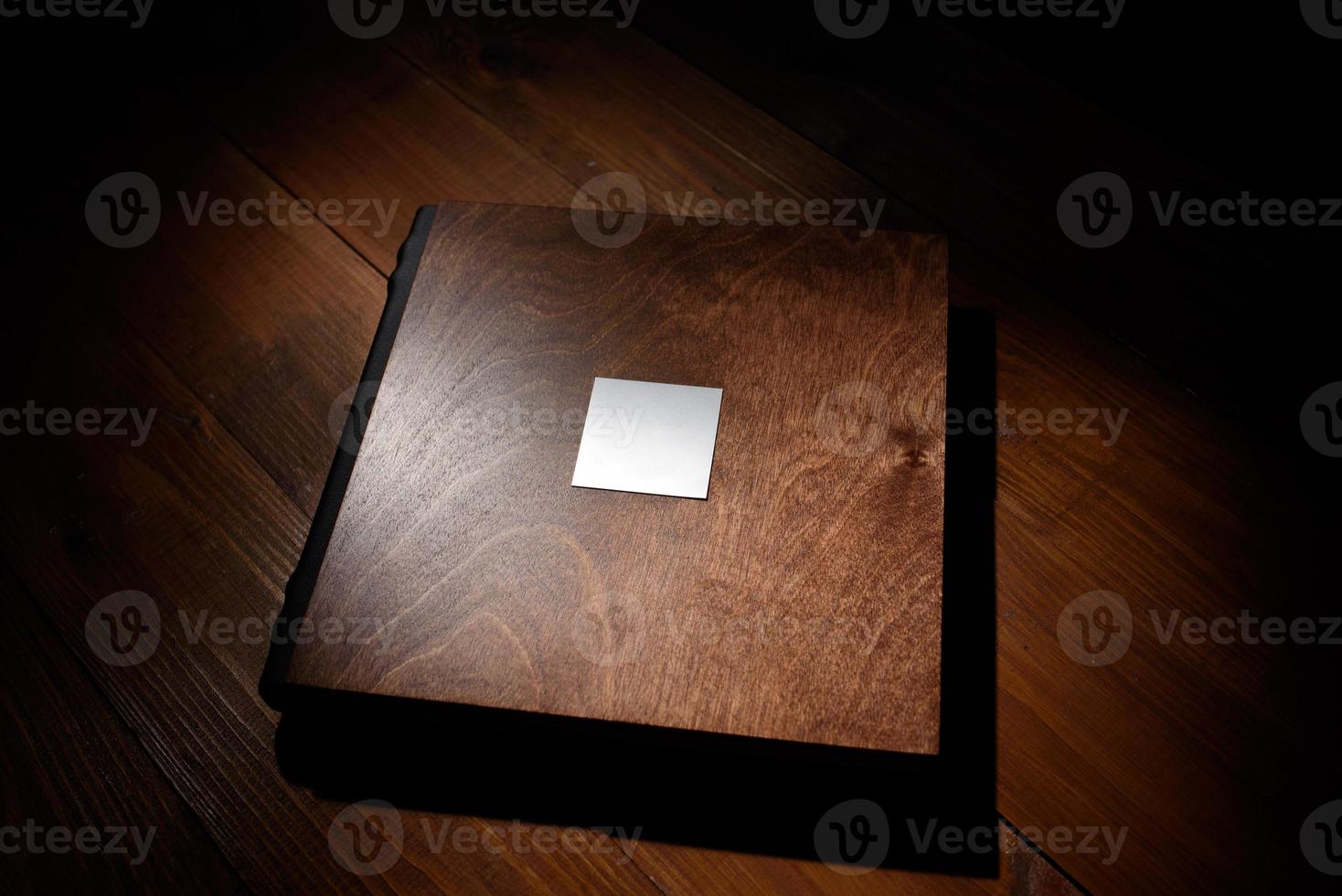 Photo book in a wooden cover on a wooden table. Hard light