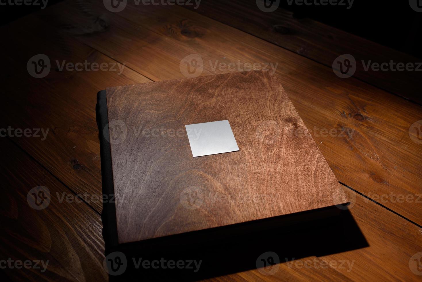 Photo book in a wooden cover on a wooden table. Hard light