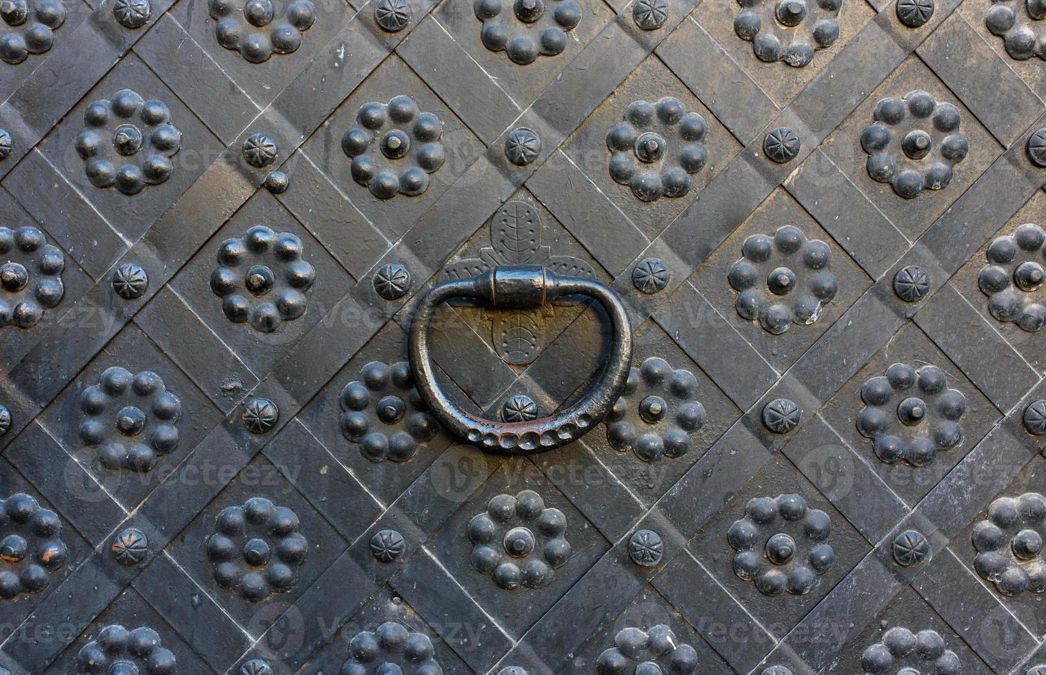 Elements of architectural decoration of ancient buildings, an old metal forged door and lattice gates, a doorknob and a knocker. On the streets in Lviv, public places. photo