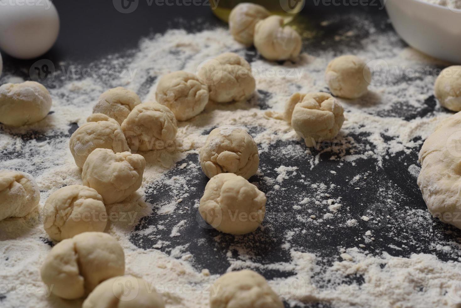 Pieces of dough in the form of a circle on a black background. Modeling of dumplings. Traditional Ukrainian cuisine. photo