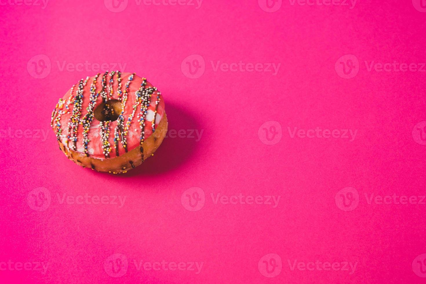 close up of a pink donut on a pink background photo