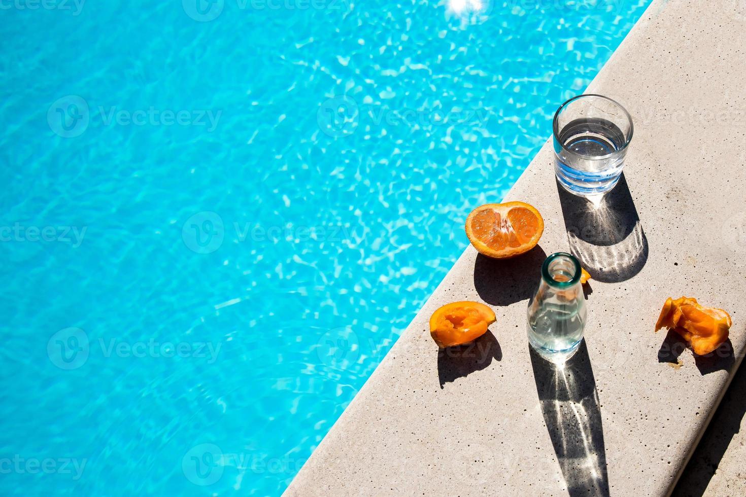 Some glasses and fruits next to the pool photo