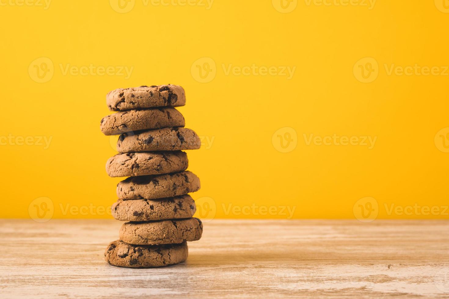 una torre de galletas con trocitos de chocolate sobre un fondo amarillo foto