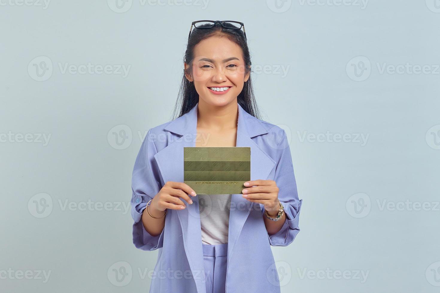 Portrait of smiling young Asian woman holding vehicle book in good mood isolated on white background photo