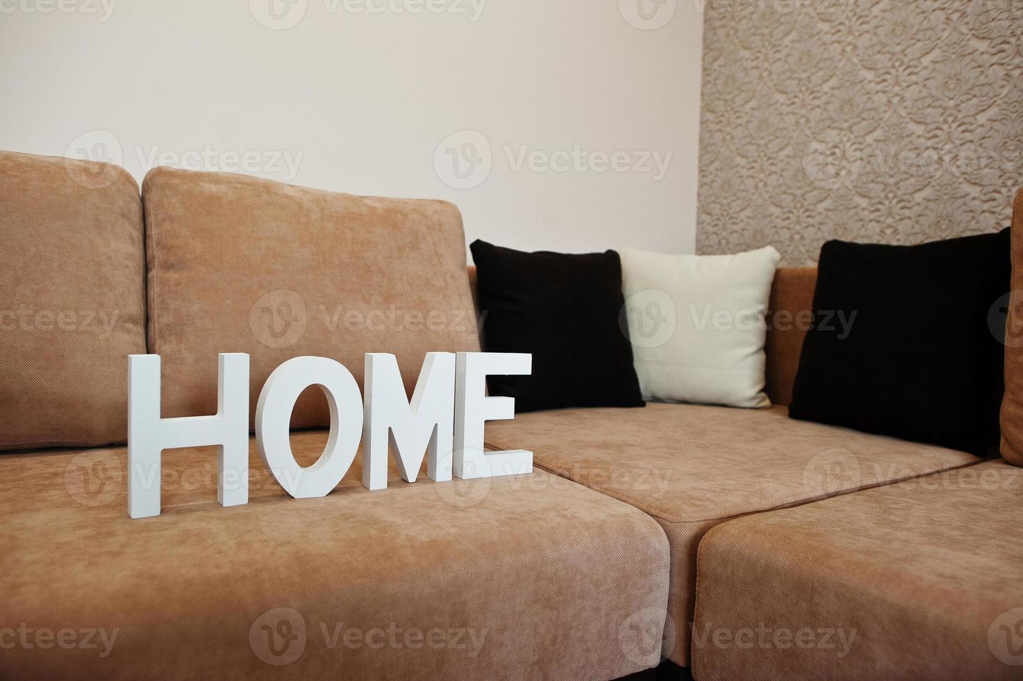 Letras blancas de madera en casa en el sofá cama de la esquina del café en la sala de luz foto