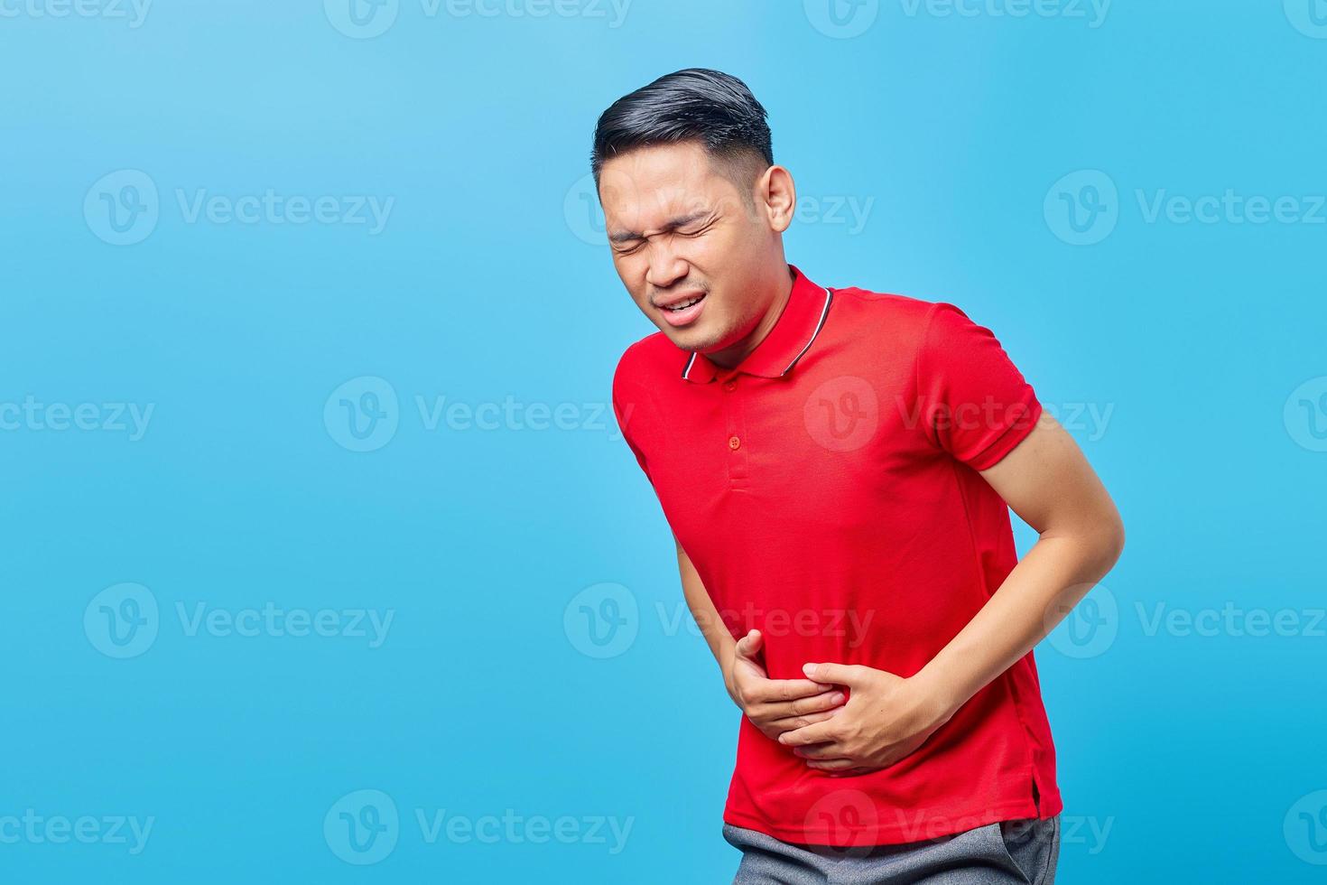 Portrait of sick young handsome Asian man with stomachache health problems diarrhea discomfort, constipation in intestine isolated on blue background photo