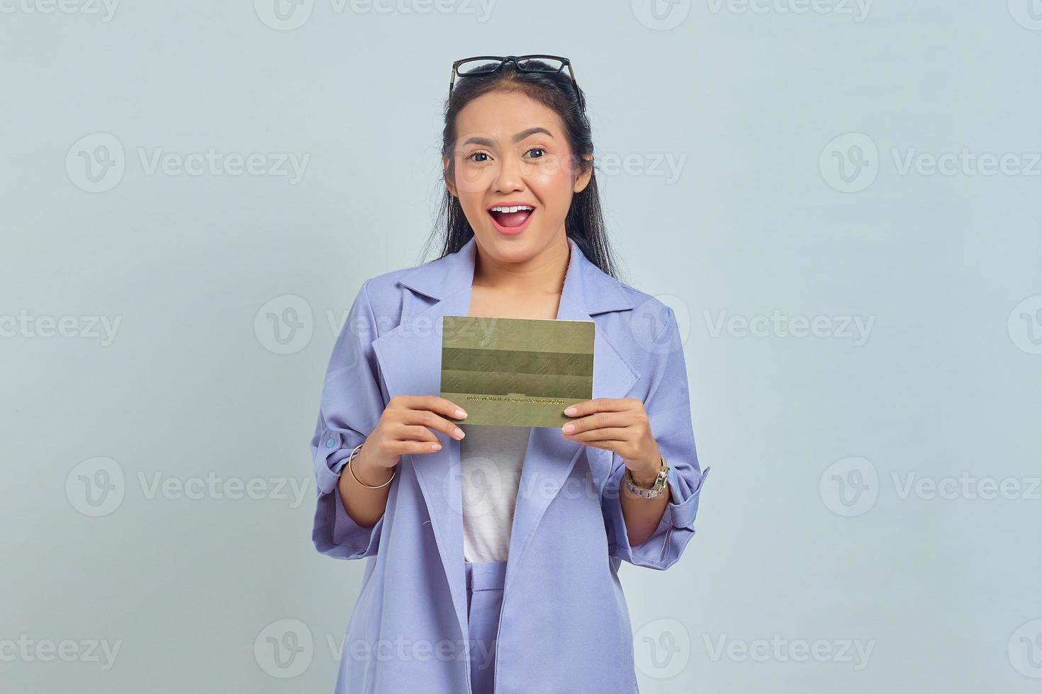 Portrait of cheerful young Asian woman holding vehicle book in good mood isolated on white background photo