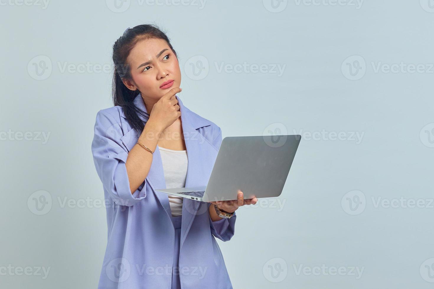 Portrait of pensive young Asian woman receiving project emailed on laptop isolated on white background photo