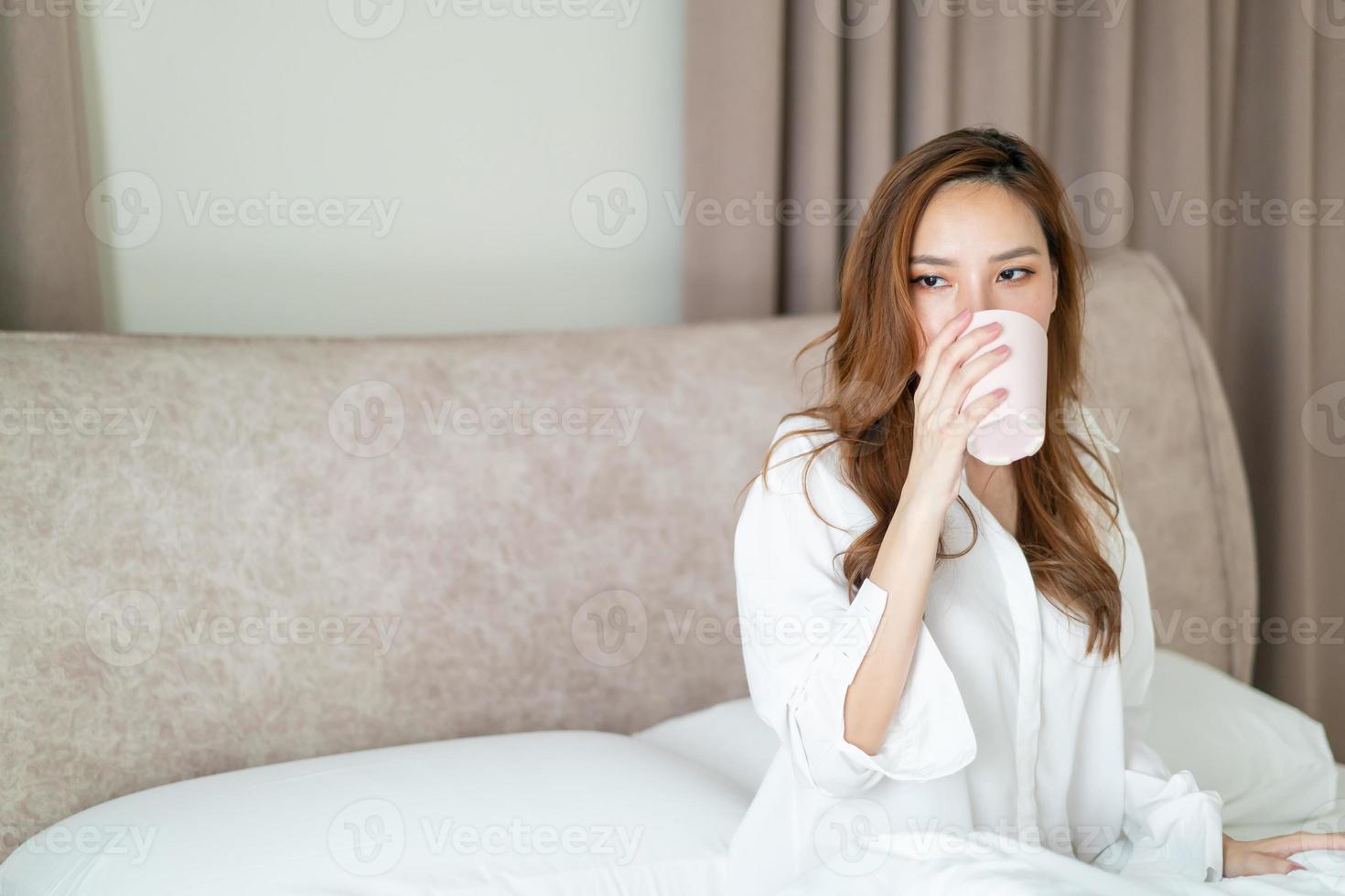 portrait beautiful woman wake up and holding coffee cup or mug on bed photo