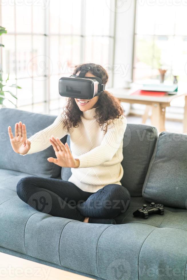 Latin woman using a virtual reality headset on sofa photo