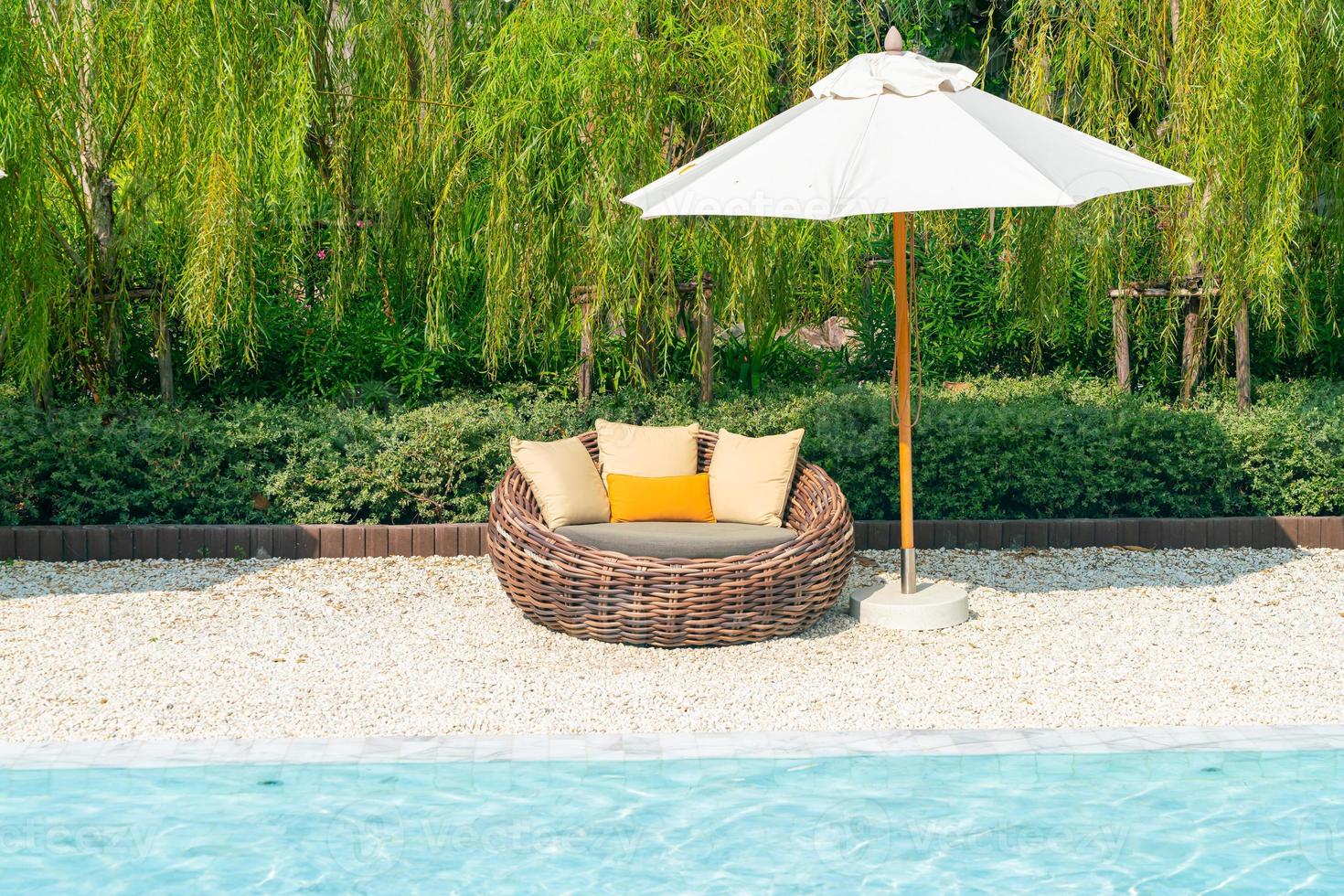 outdoor patio chair with pillow and umbrella around swimming pool photo