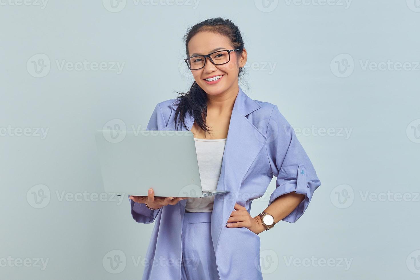 Portrait of cheerful young Asian woman using laptop and looking at camera isolated on white background photo